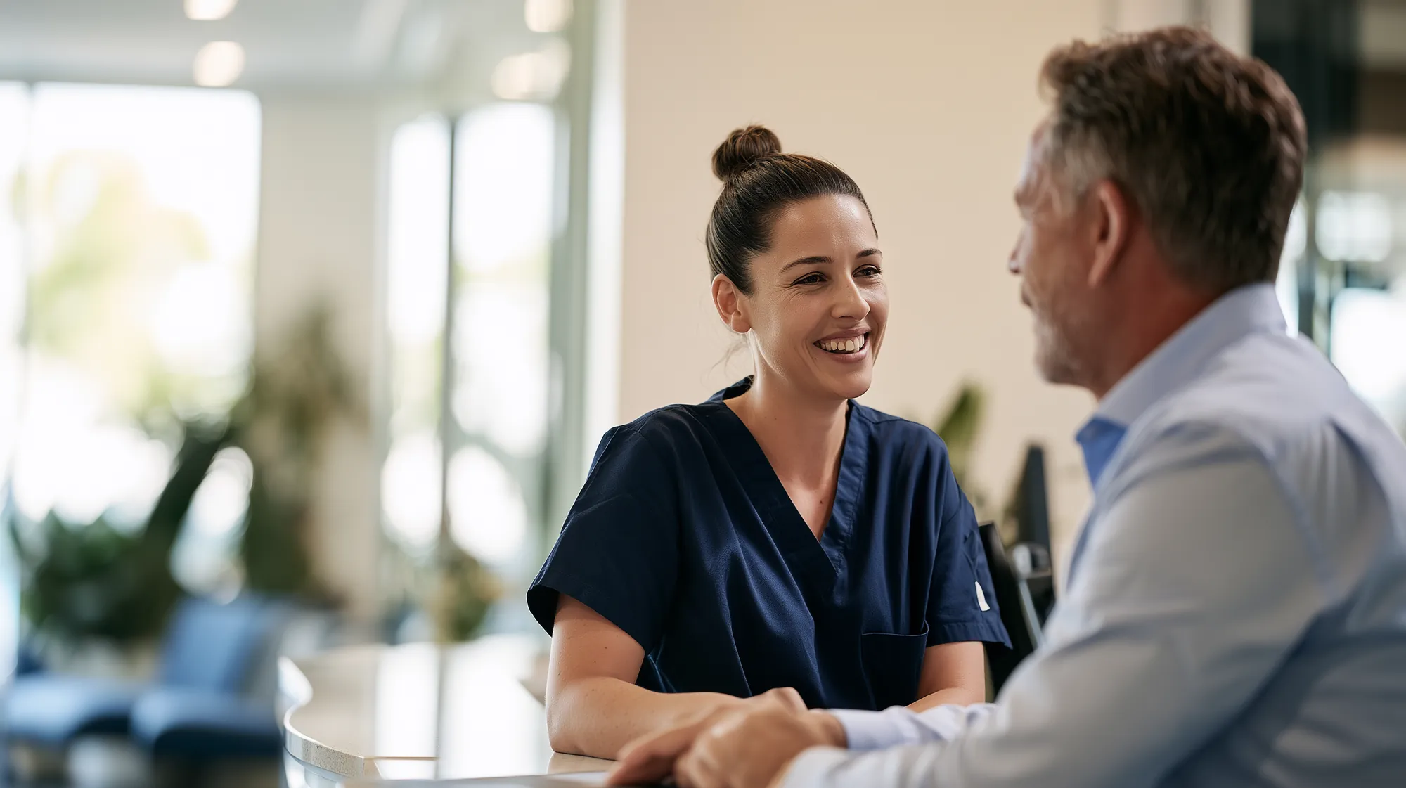 A physiotherapist and a practice manager talking at a clinic reception desk